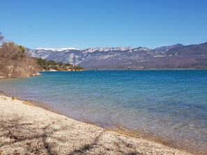 Una vista despejada de un lago con orilla pedregosa y montañas al fondo.