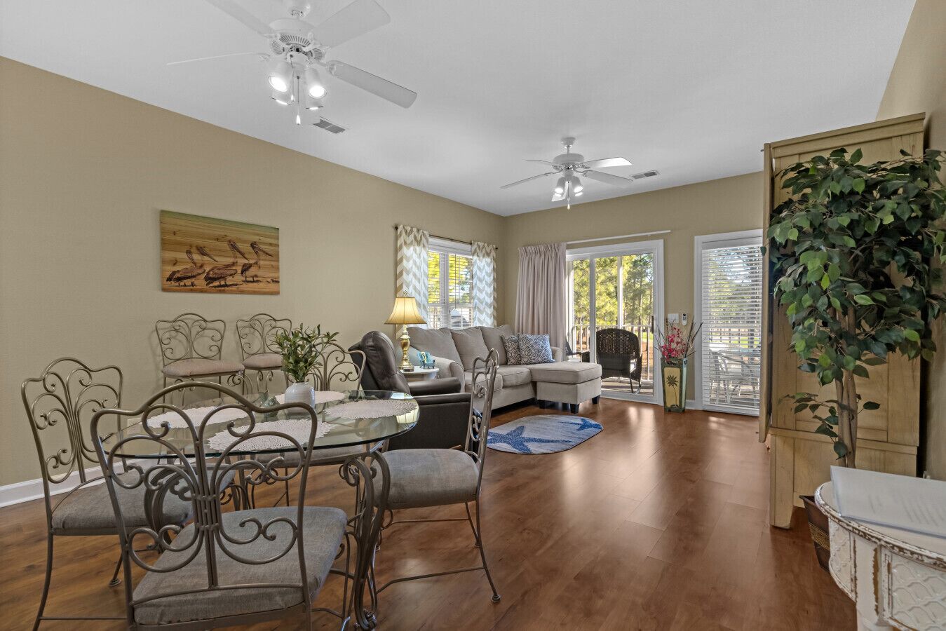 A spacious living room with a glass coffee table, a sofa, and a dining area with metal chairs.
