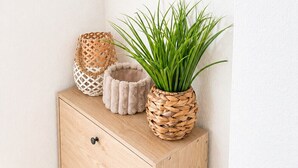 Un comò di legno con uno specchio, un cesto di vimini e una pianta in vaso.