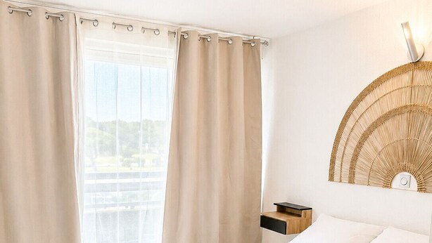 Una camera da letto con un letto grande, un comodino, una lampada a parete e vista dalla finestra.