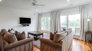 Ein Wohnzimmer mit Flachbildfernseher, zwei Sofas, einem Couchtisch und einem Deckenventilator.