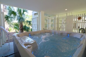 A hot tub with a white exterior, surrounded by a white fence, and a palm tree in the background. - Easy Beach Access | Private Hot Tub + Elevator Retreat (Tybee Island)