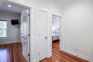 A room with hardwood flooring, white walls, and a bed with a floral bedspread. - Easy Beach Access | Private Hot Tub + Elevator Retreat (Tybee Island)
