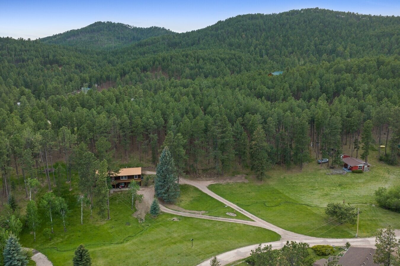 Ein bewaldetes Gebiet mit einem Gebäude, blauem Himmel und einer hügeligen Landschaft.
