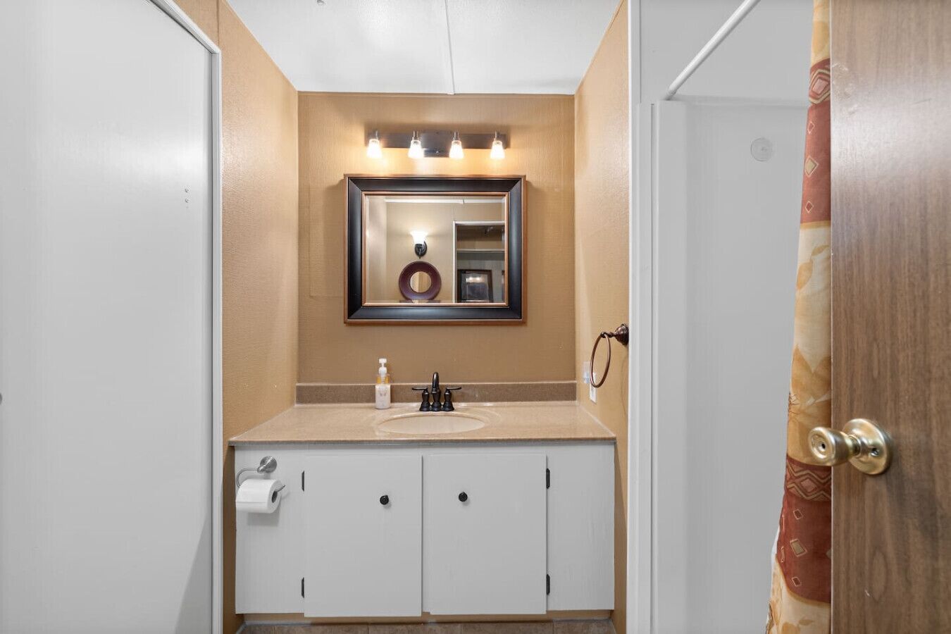 A bathroom with a sink, mirror, and two cabinets.