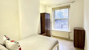 Une chambre à coucher avec un lit, une fenêtre, un radiateur et une armoire.