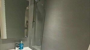 Une salle de bain moderne avec un lavabo blanc, un miroir et une douche.