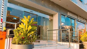 A modern building with a glass facade, a metal staircase, and potted plants in front. - GOSONA LBASIKA HOTEL (Madinah)