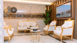 A luxurious lobby with a marble floor, a sofa set, and a large television on the wall. - GOSONA LBASIKA HOTEL (Madinah)