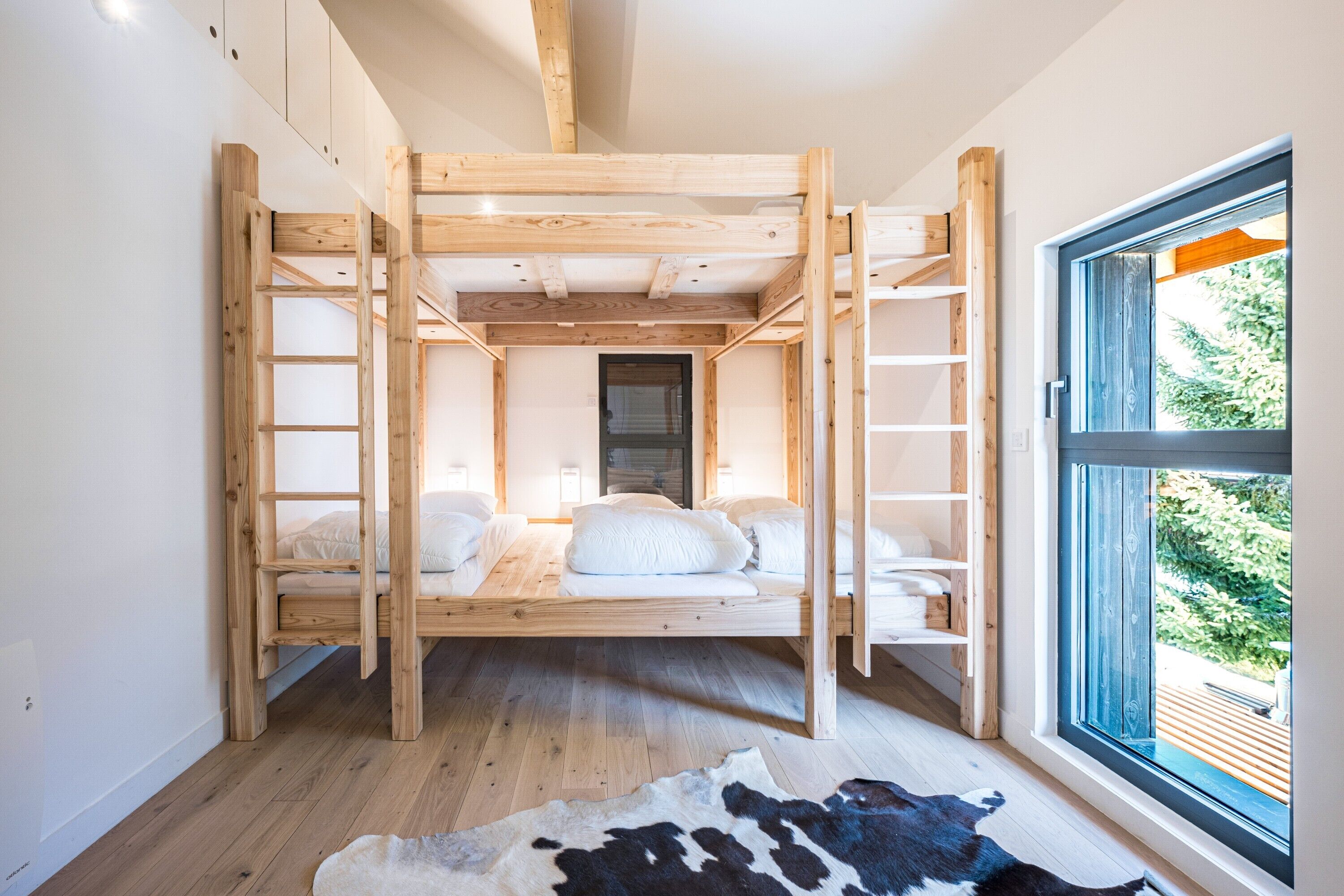 Una habitación con literas, una ventana con vistas y suelo de madera.