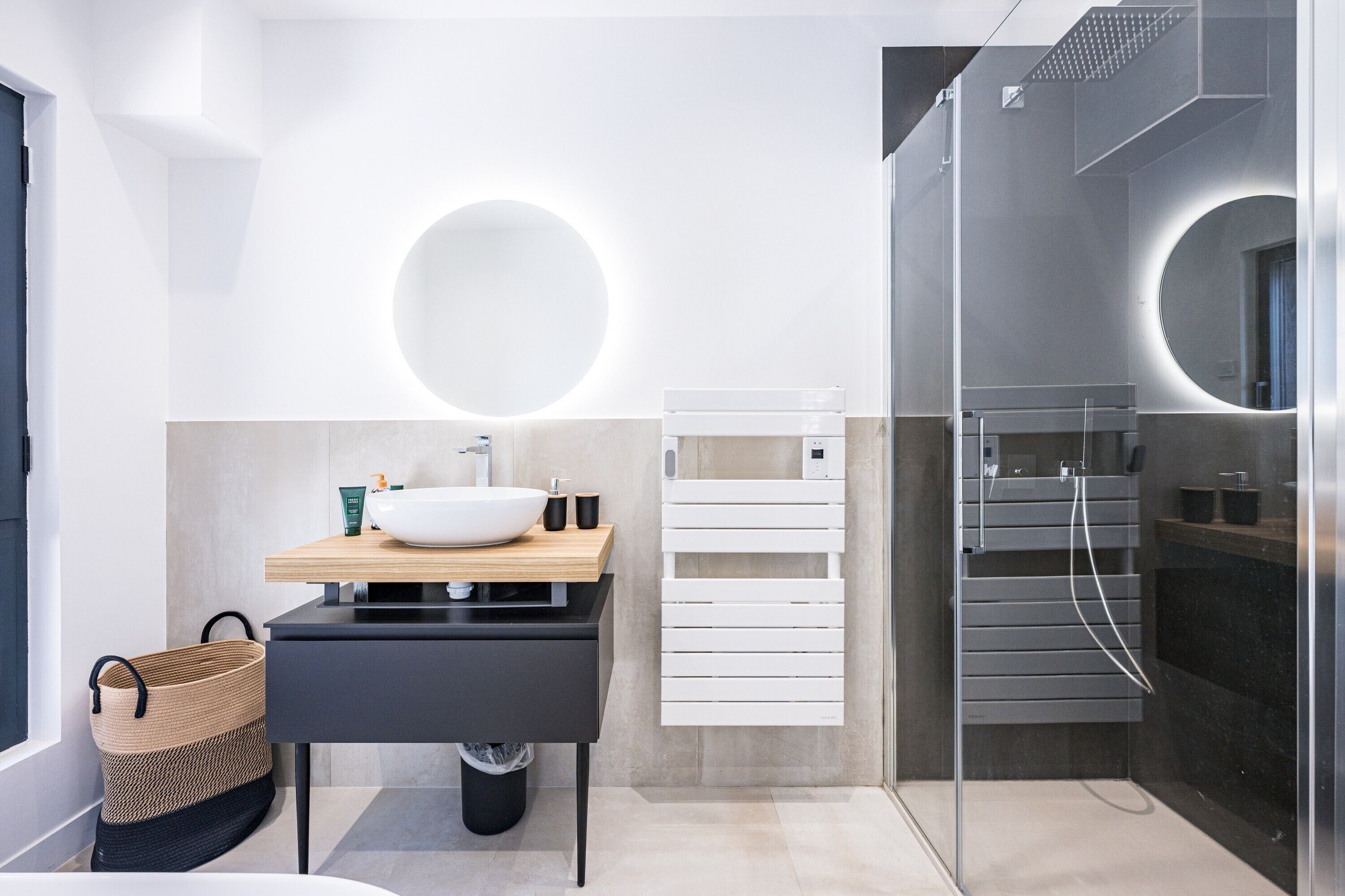 Un baño moderno con un lavamanos grande de color blanco, un espejo, una ducha y un perchero para toallas.