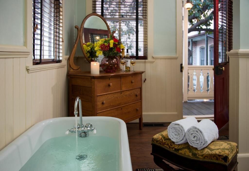A bathroom with a bathtub, wooden dresser, and a mirror.