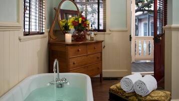 A bathroom with a bathtub, wooden dresser, and a mirror.