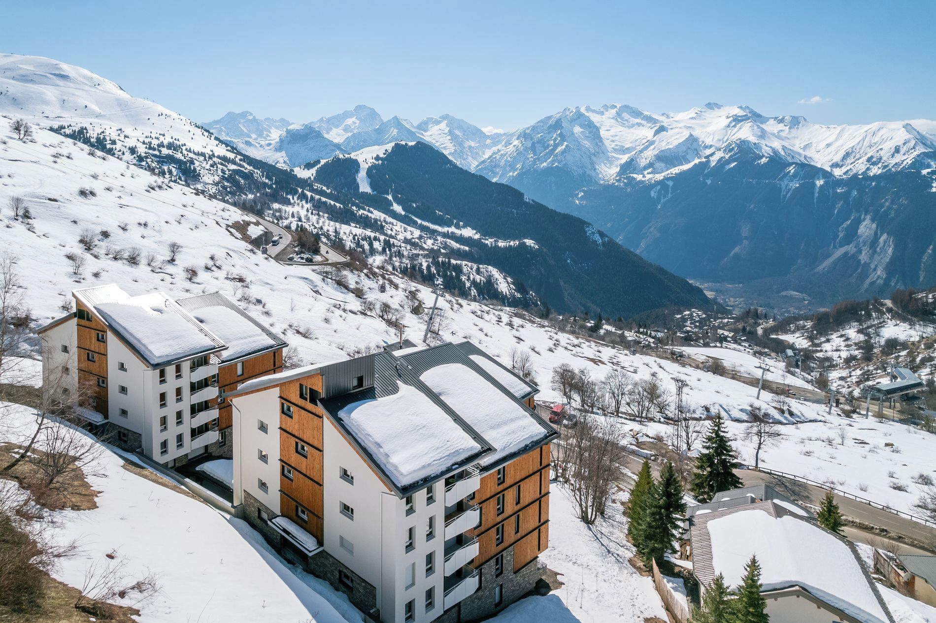 Ein modernes Gebäude mit geneigtem Dach, umgeben von schneebedeckten Bergen und einem klaren Himmel.