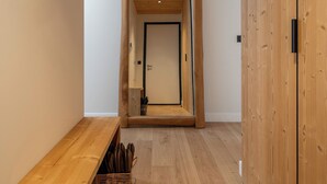 Un couloir avec un plancher en bois, un banc et une porte en bois.