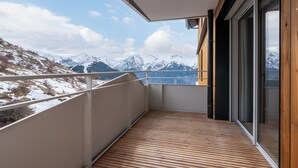 Un balcon doté d’un plancher en bois et offrant une vue sur des montagnes enneigées.