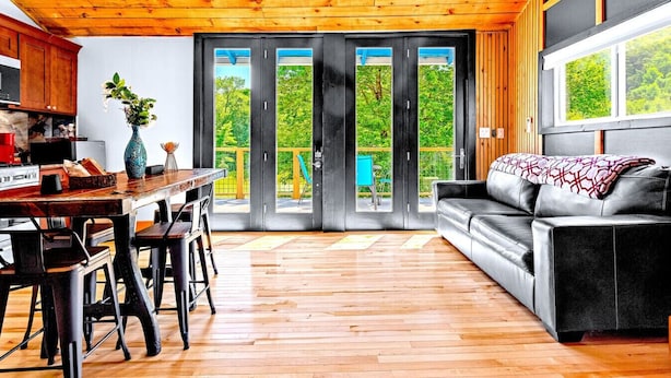 Et moderne køkken med træskabe, et spisebord med stole og en stor skydedør, der fører til en balkon med havemøbler.
