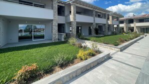 A modern multi-story residential building with balconies, large windows, and a landscaped garden area. - Armonia - Two Bedroom Apartment, Sleeps 6 (Desenzano del Garda)