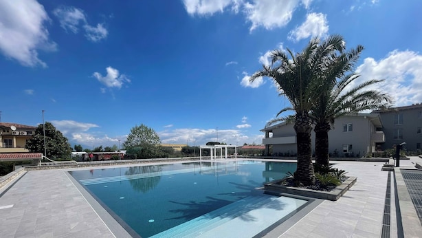 A rectangular swimming pool with clear blue water, surrounded by a tiled deck. - Armonia - Two Bedroom Apartment, Sleeps 6 (Desenzano del Garda)