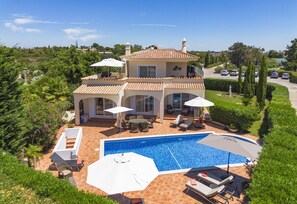 Ein zweistöckiges Haus mit Schwimmbad, Gartenmöbeln und einem Garten.