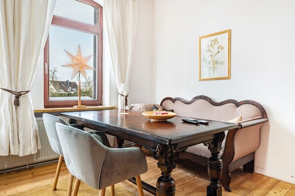 Uma área de refeições com uma mesa de madeira, duas cadeiras, um sofá, um adorno em formato de estrela e um quadro na parede.