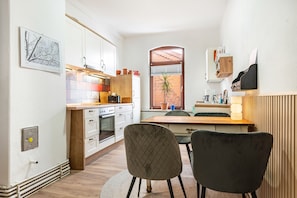 Una cocina compacta con armarios blancos, una encimera de madera y una zona de comedor con dos sillas.