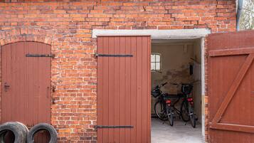 A brick building with two wooden doors, a bicycle, and two tires outside.