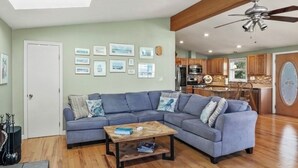 A living room with a sectional sofa, a coffee table, and a ceiling fan.