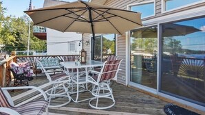 A covered outdoor patio with a table and chairs, a large umbrella, and a view of the surrounding area.