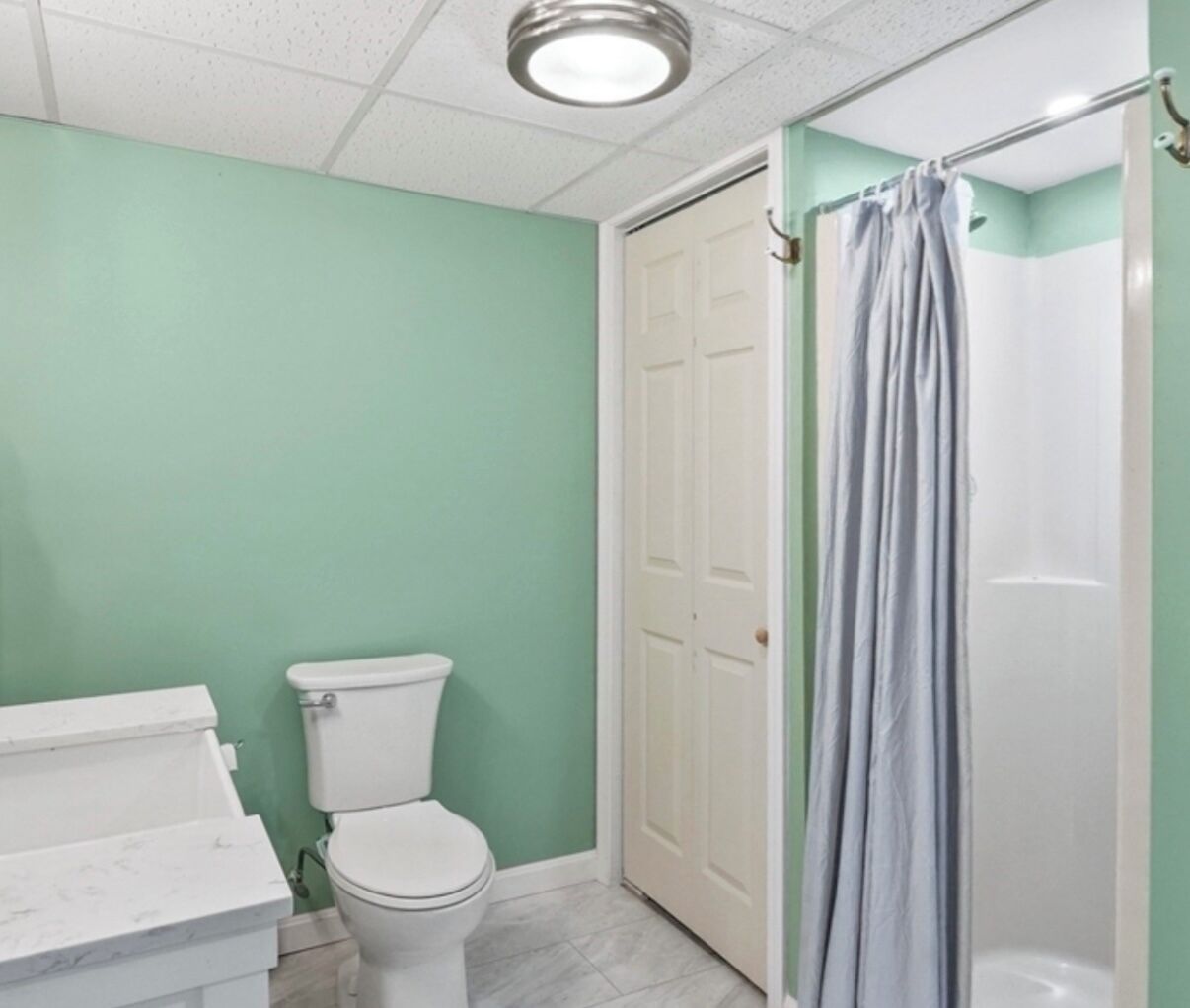 A bathroom with a toilet, a shower curtain, and a white door.