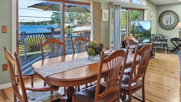 A dining area with a table and chairs, large windows, and a view of the outdoors.