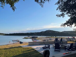 Un patio junto al lago con mobiliario exterior y vistas al agua.