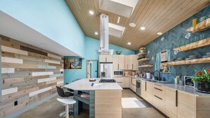 Une cuisine moderne dotée d’un îlot central, de meubles en bois et d’un dosseret orné d’un motif en chevrons.