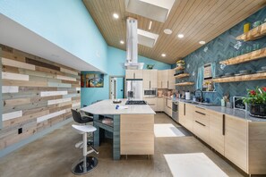 A modern kitchen with a central island, wooden cabinetry, and a herringbone-patterned backsplash. - "The Drive Thru"@Lake Travis 
A proper GAME ROOM you can literally DRIVE Thru (Leander)