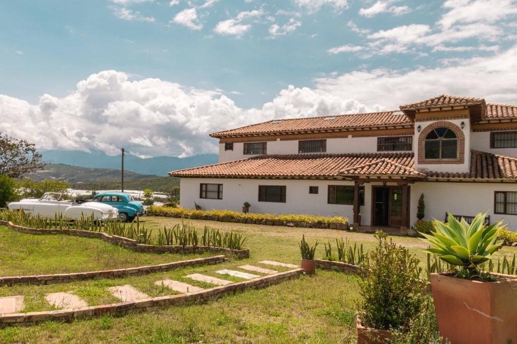 Une maison à deux étages, avec un toit en tuiles, un porche à l’avant et une pelouse bien entretenue, ainsi qu’un chemin menant à l’entrée.