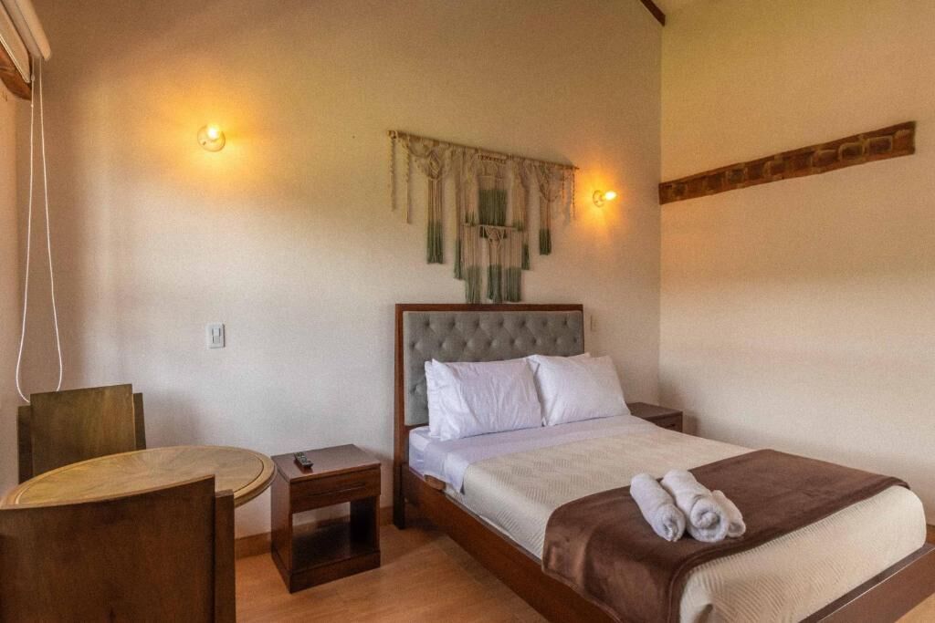 A bedroom with a bed, a small table, and a chair.