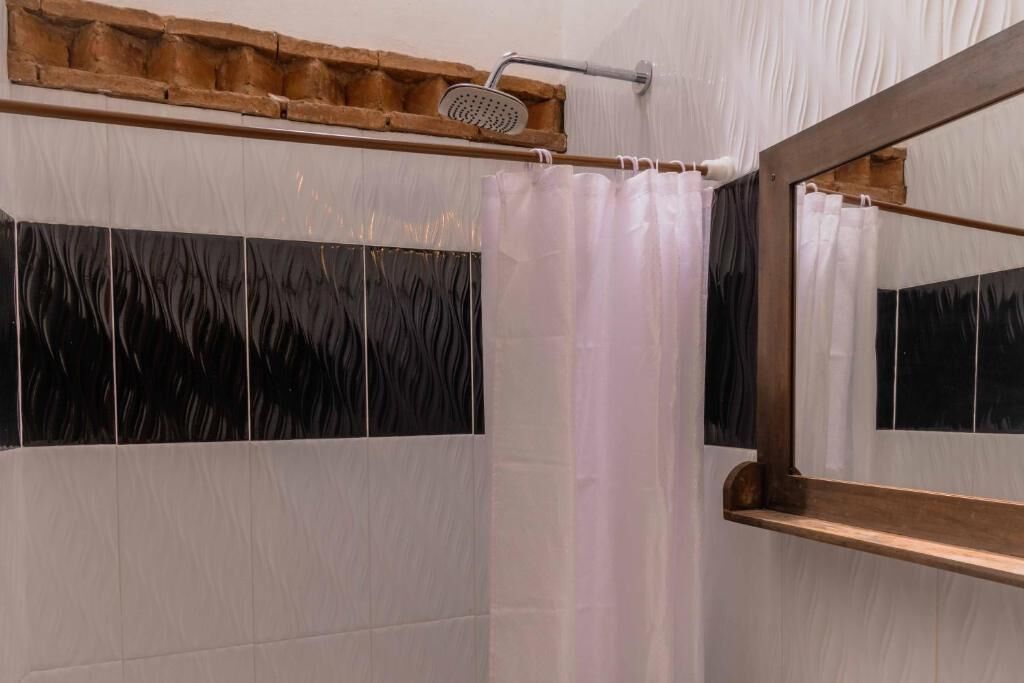 Ducha con estante de madera, cabezal de ducha y espejo.