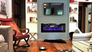 Ein Wohnzimmer mit Fernseher, Kamin, einem roten Ledersessel und einem Couchtisch mit einem Spielzeug.