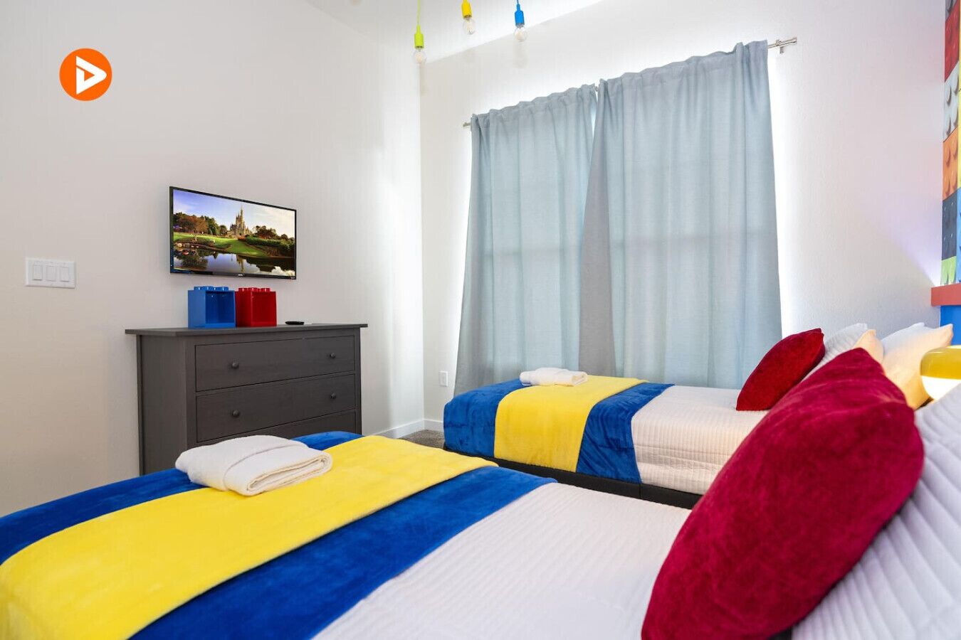 Ett hotellrum med två sängar, en tv på väggen, en byrå och ett fönster med gardiner.