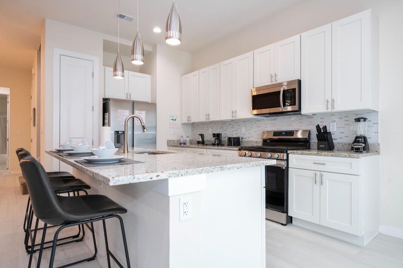 A modern kitchen with white cabinets, stainless steel appliances, and a granite countertop.