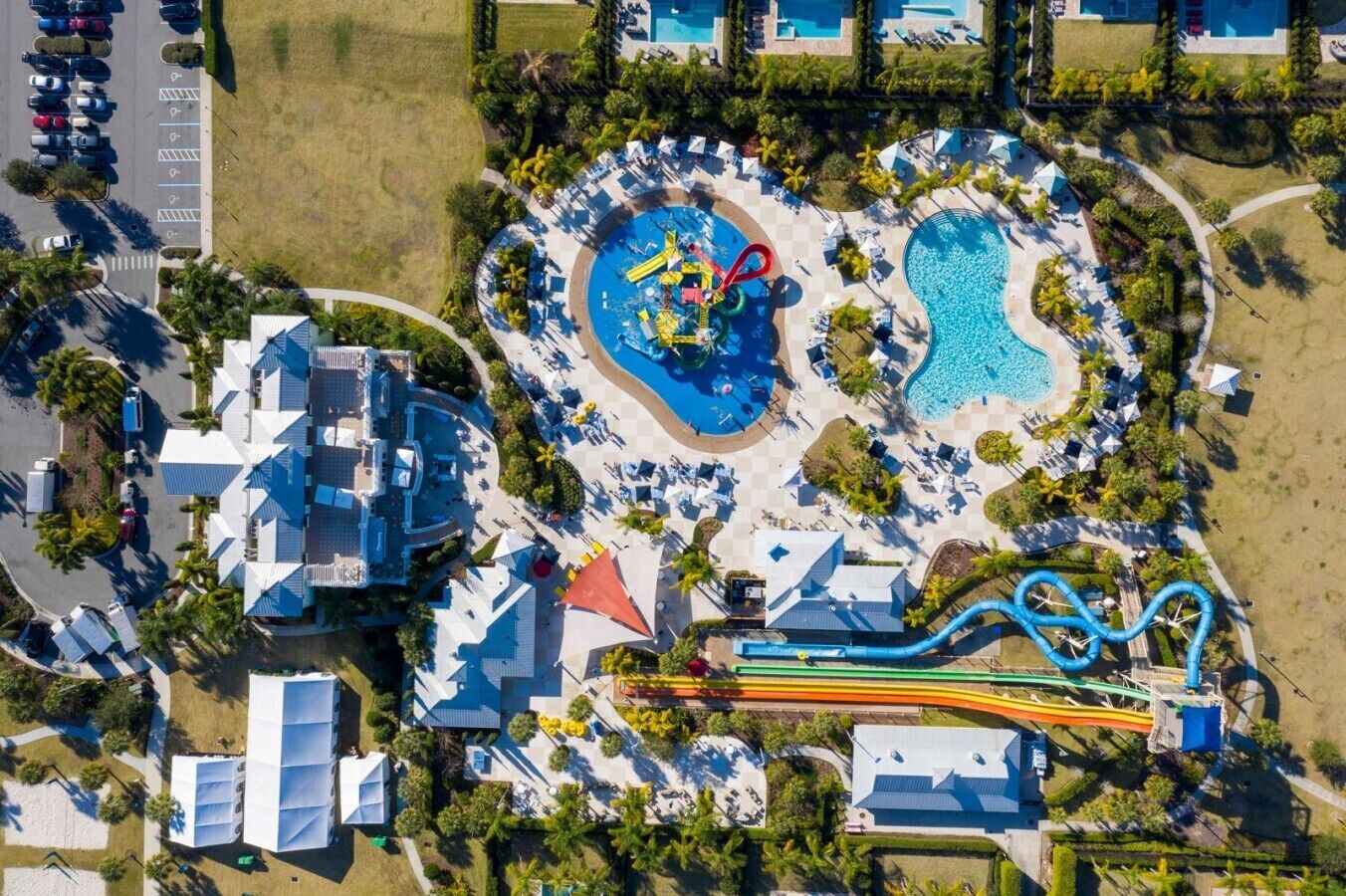 Vista aérea de un complejo turístico con varias piscinas, un parque acuático y un estacionamiento.