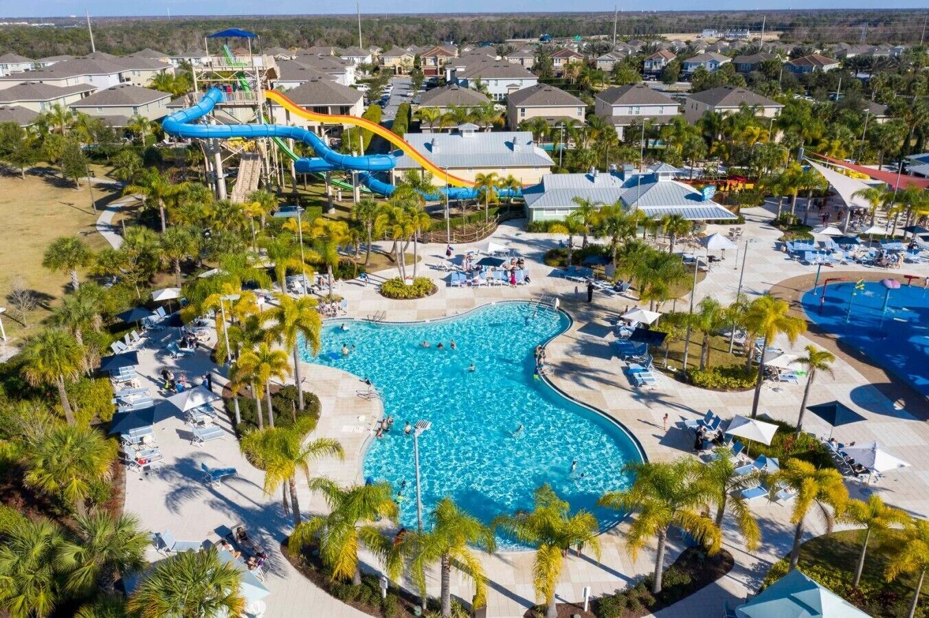 A resort with a large swimming pool, a water park with slides, and a beach area.
