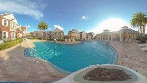 A swimming pool surrounded by residential buildings, with a clear sky above. - 7532 Perfect Home 5 Minutes from Disney – 5BD 15P (Kissimmee)