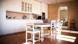 A spacious kitchen with white cabinetry, a dining table with chairs, and a stone wall.