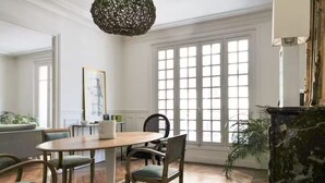 A dining area with a round table, chairs, and a hanging light fixture. - Beaut. Hausmannian flat in Oberkampf near Marais (Paris)