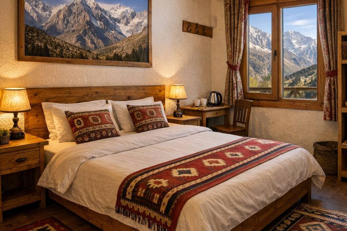 Un dormitorio acogedor con una cama de madera, dos lámparas de noche, vistas a montañas a través de una ventana y un cuadro grande de montañas en la pared.