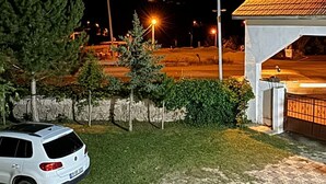 Um carro branco estacionado em um pavimento estampado, um edifício com telhado de azulejos e uma montanha ao fundo.