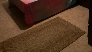 Camera da letto con un letto, un comodino, una lampada, una TV a muro e una finestra con tende.