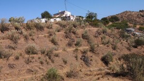 Un pendio con vegetazione rada e un edificio con facciata bianca.
