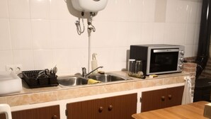 Una cucina con forno a microonde, lavello e pensili.